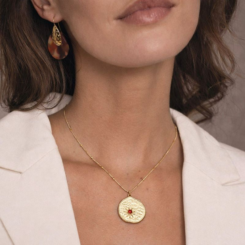 Femme portant collier evjf dore avec medaille ronde texturee et pierre rouge idee cadeau enterrement vie jeune fille