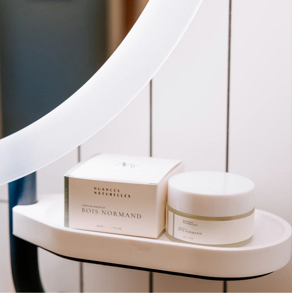 Crème visage naturelle ‘Bois Normand’ de Nuances Naturelles, présentée sur une étagère de salle de bain blanche avec miroir, soin beauté élégant à offrir lors d’un EVJF.