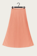 Jupe longue plissée couleur corail suspendue sur cintre, tenue fluide et élégante pour un look EVJF.