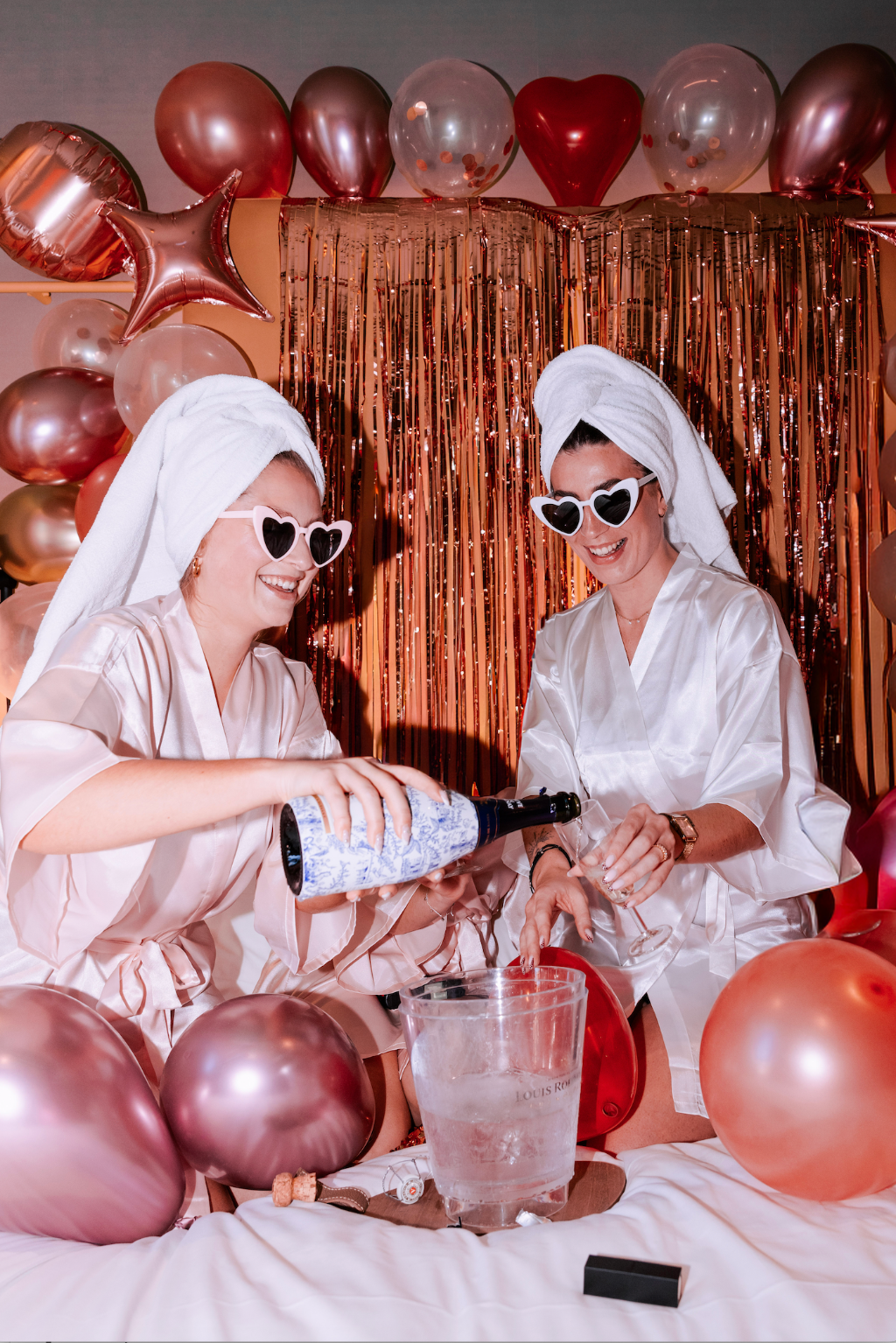 Amies celebrant un EVJF lors dune soiree cocooning avec kimono, champagne et decoration de ballons rose gold.