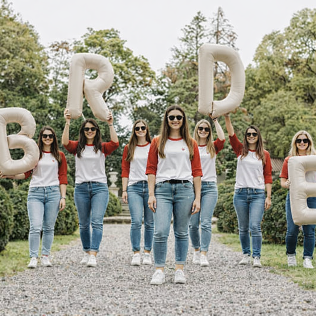 Groupe de femmes portant des t-shirts EVJF blancs a manches rouges lors dune sortie en plein air avec ballons bride.