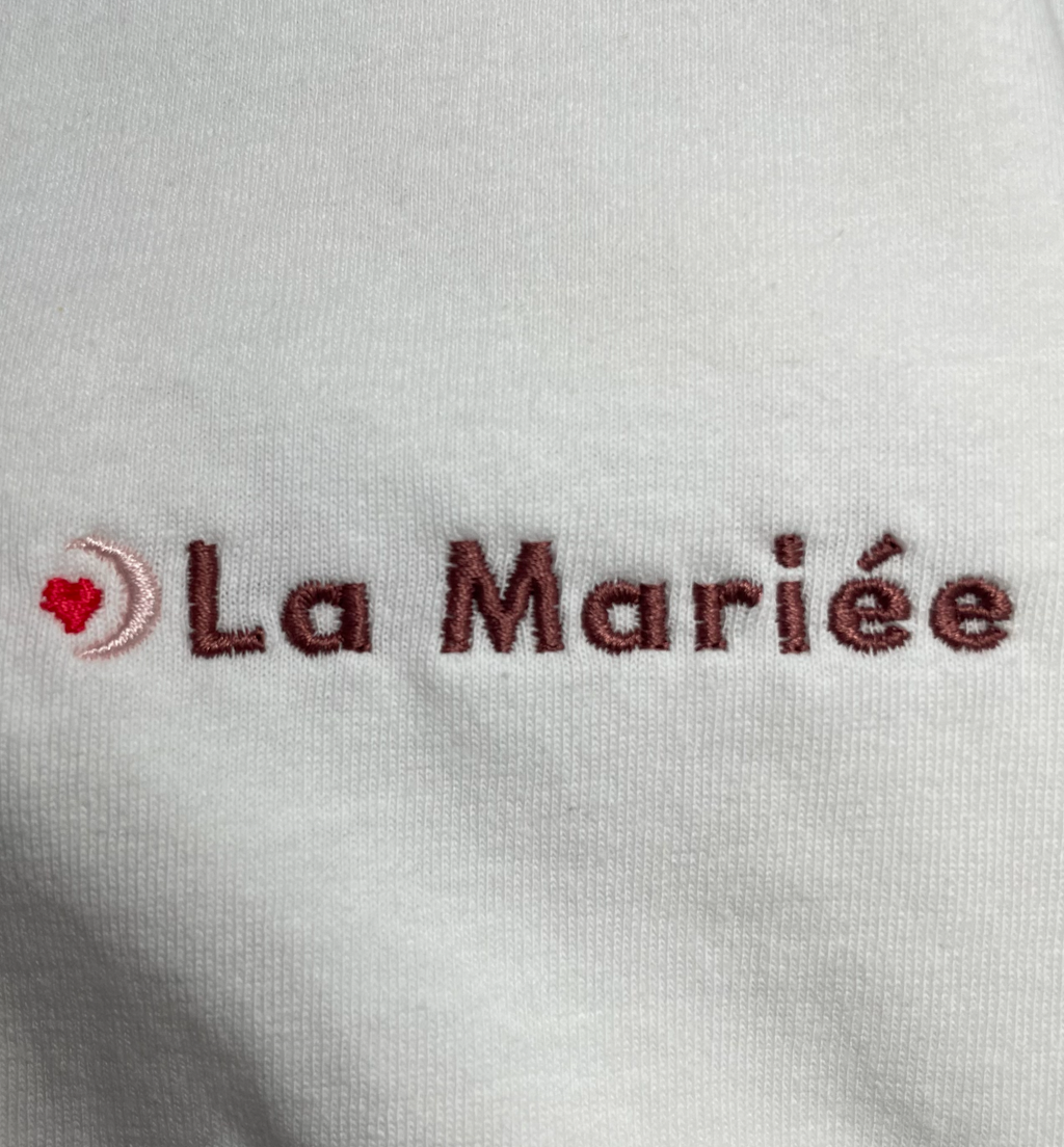 Détail de la broderie ‘La Mariée’ sur t-shirt blanc EVJF, finition brodée élégante pour la future mariée.