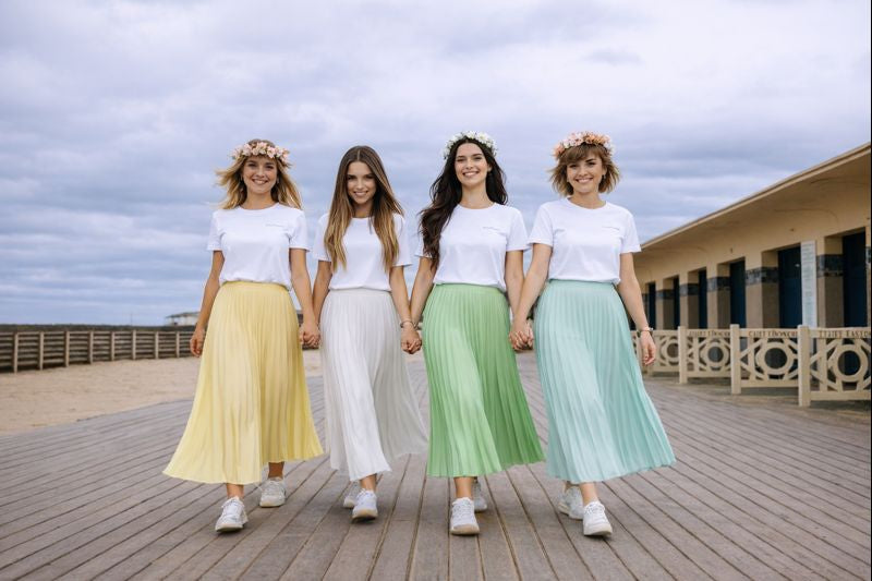 Groupe damies marchant ensemble lors dun EVJF, portant des jupes plissees pastel et des t shirts blancs coordonnes.