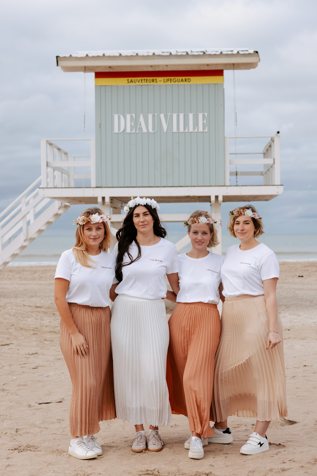 Groupe de femmes en tenue EVJF avec jupes plissees et t shirts blancs sur la plage de Deauville