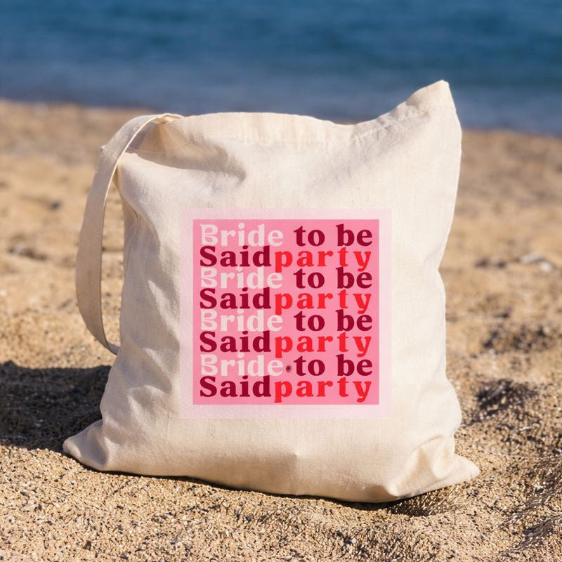 Tote bag EVJF en toile pose sur la plage avec message bride to be said party, sac tendance pour future mariee et enterrement de vie de jeune fille.